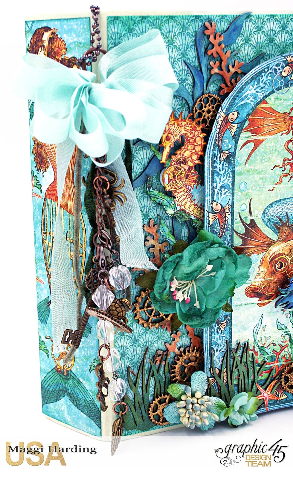 Detail of front cover. I used some charms and a Tim Holtz chain and charms to make the dangly "thingy" and tied a seam binding ribbon to the top.