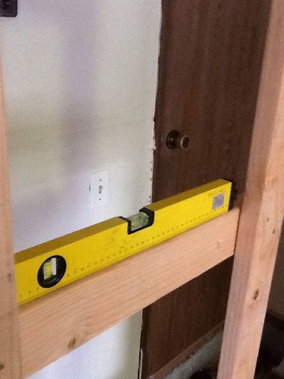 Determine the height of the shelves, cutting a 2ft piece off of a stud, screw the shelf brace into the legs at the correct height. Use a level to make sure it is straight.