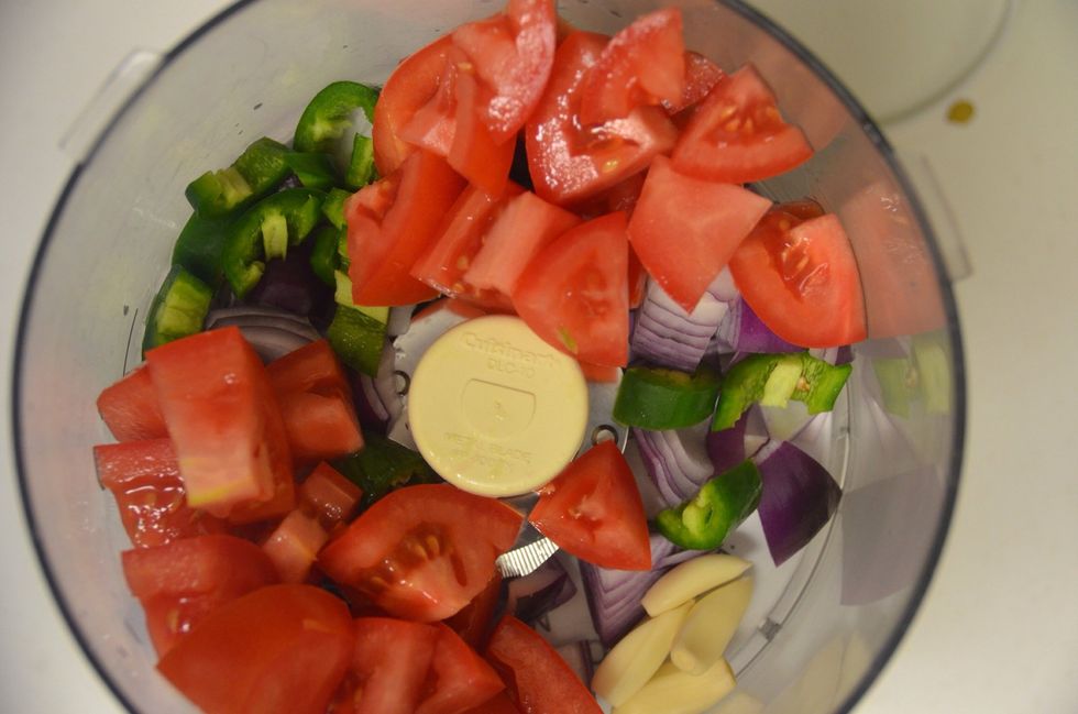 Dice the onions tomatoes and Serrano peppers and add to the food processor. Peel the garlic and add that as well. Churn it to form a pur\u00e9e.