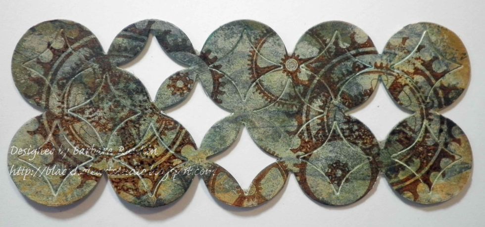 Die cut chipboard with Courtyard die. Add a wash of white gesso, distress inks, and stamp images from Sin City Stamps Steampunk'd Christmas and Art Journaling stamp plates in StazOn Spiced Chai.