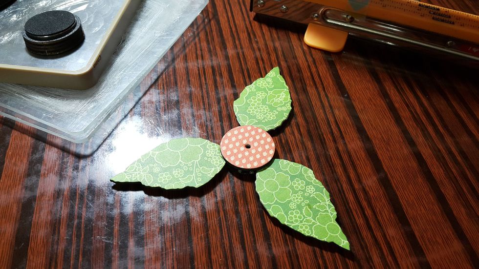 Die cut two pieces of circle chipboard pieces, adhere the leaves in between like sandwiches, punch a small hole for the black wire