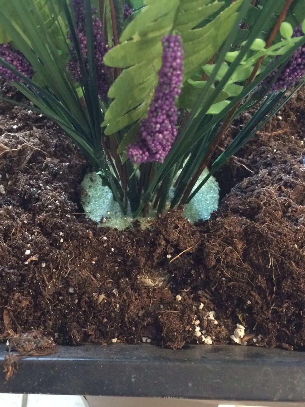 Dig a hole in your planter, then "plant" the foam. Push it in firmly, the cover with soil.