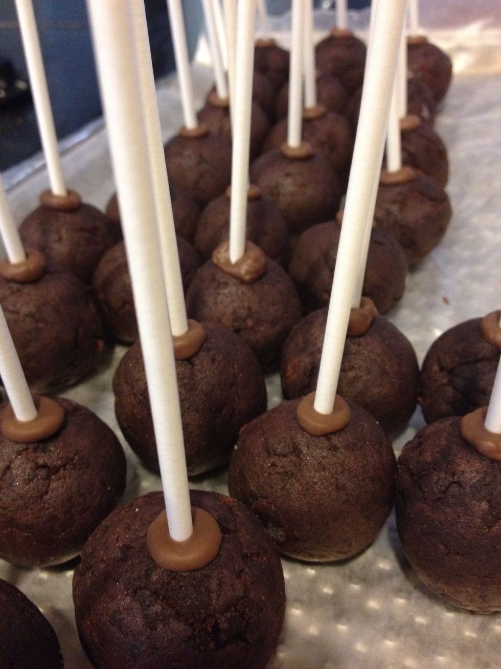 Dip a lollipop stick into the chocolate and put it into the cake ball. Allow the chocolate to cool for 5-10 minutes