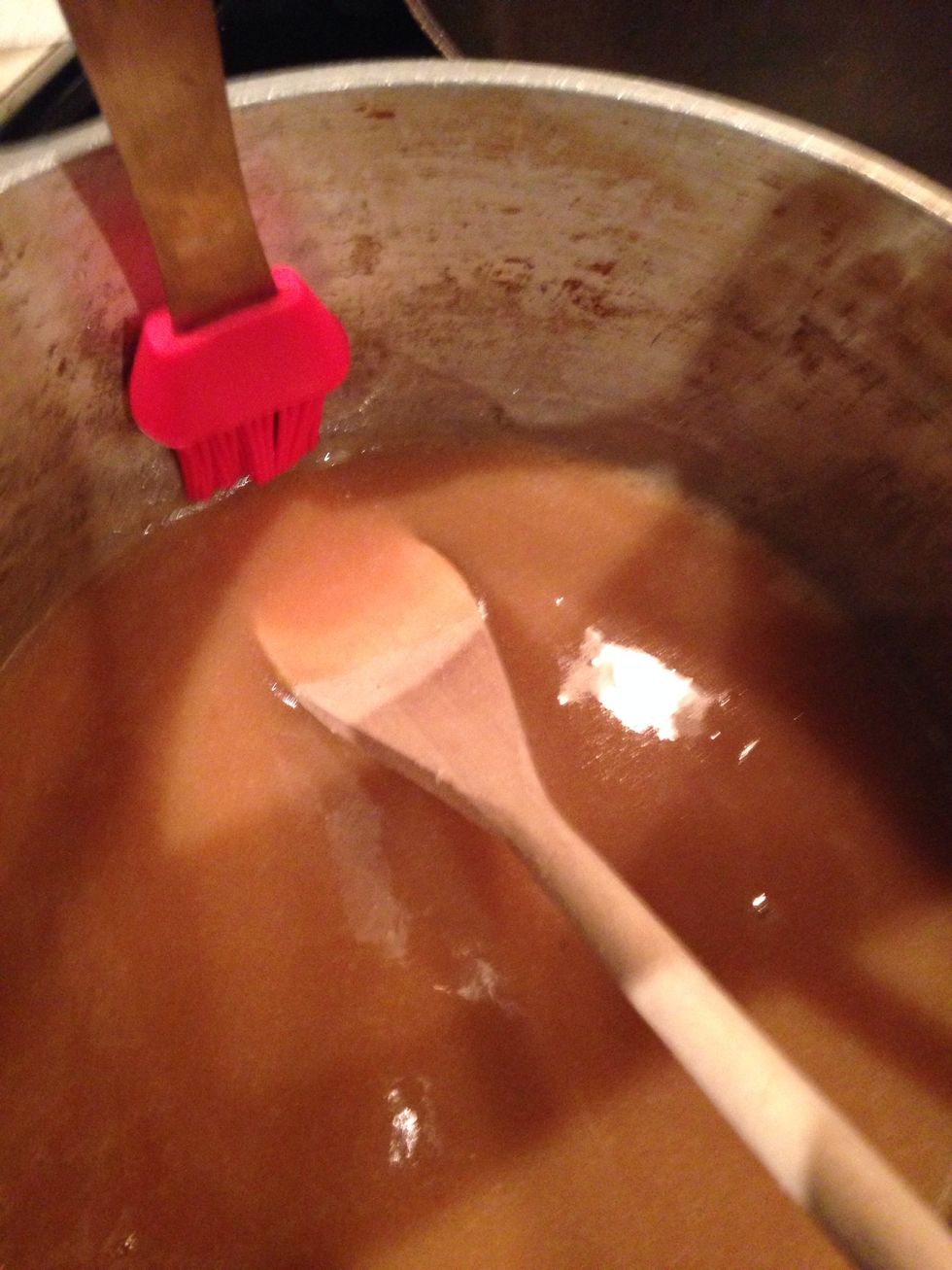Dip a pastry or any kind of small cooking brush in cold icy water;then brush the sides of the pot to melt away in sugar crystal that formed.