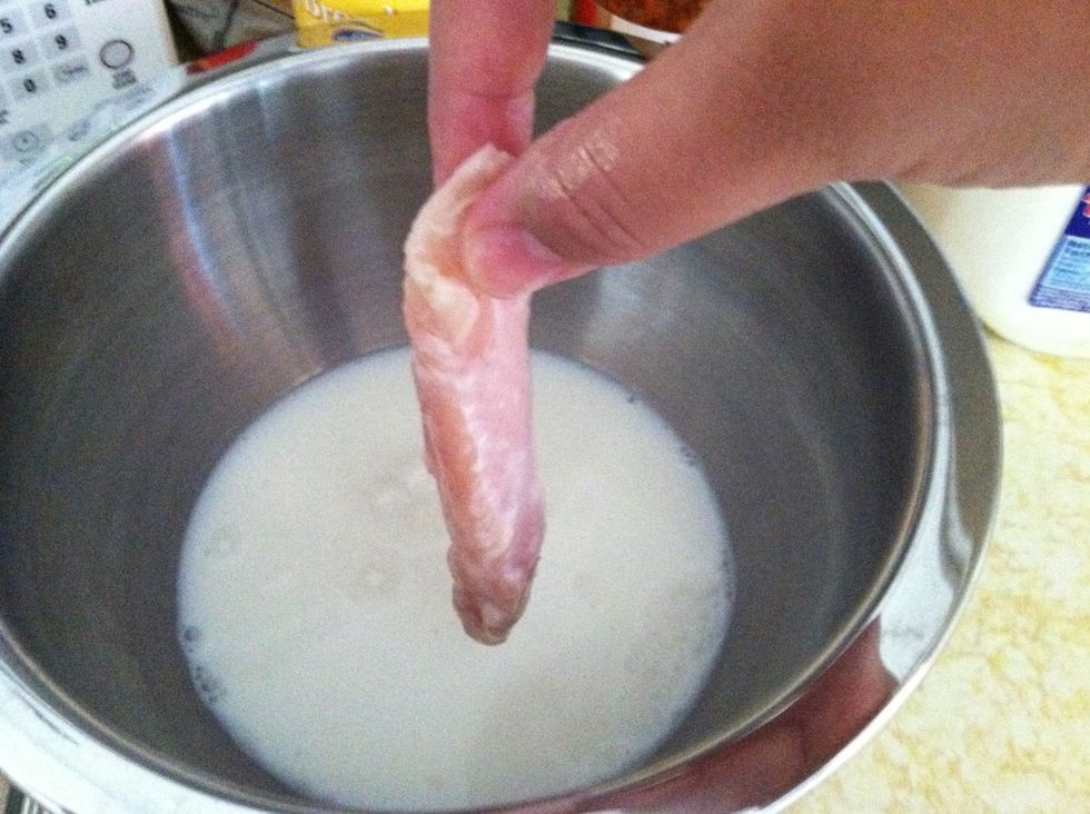 Dip a piece of chicken into the milk.
