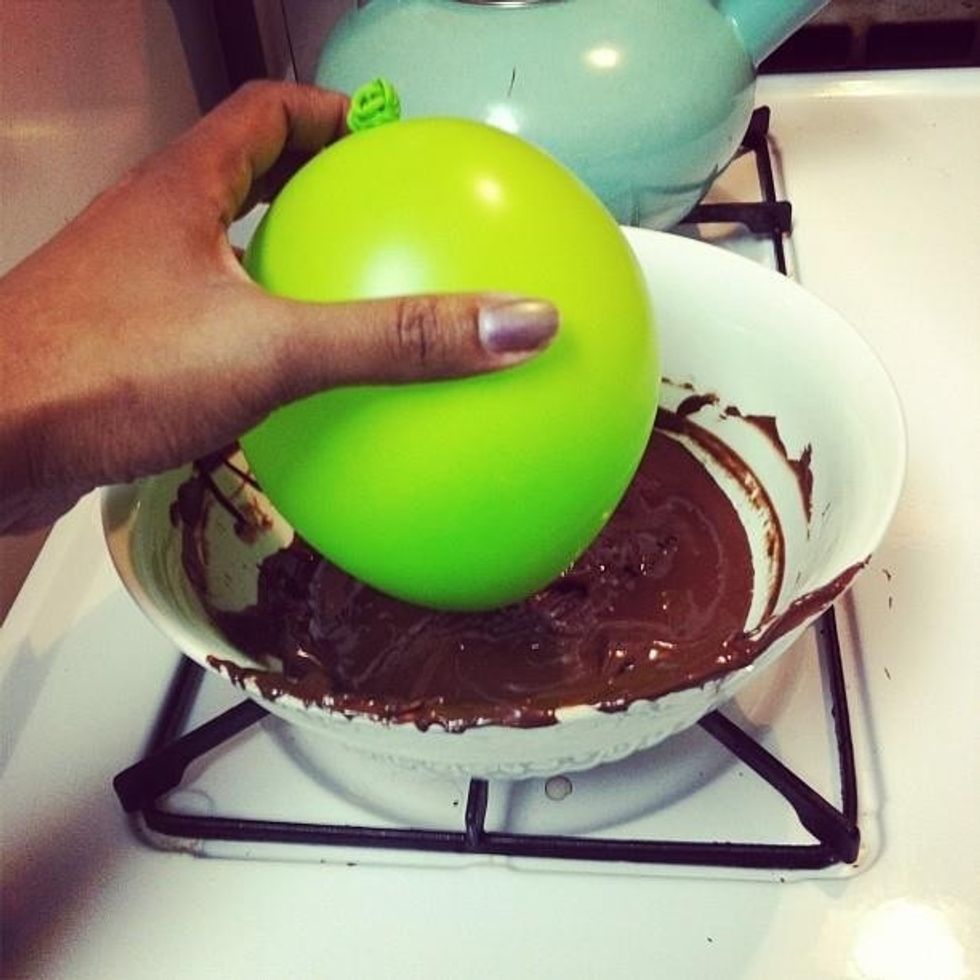 Dip balloon into chocolate - try to evenly coat it. Realize it can be trial and error. You can do this!