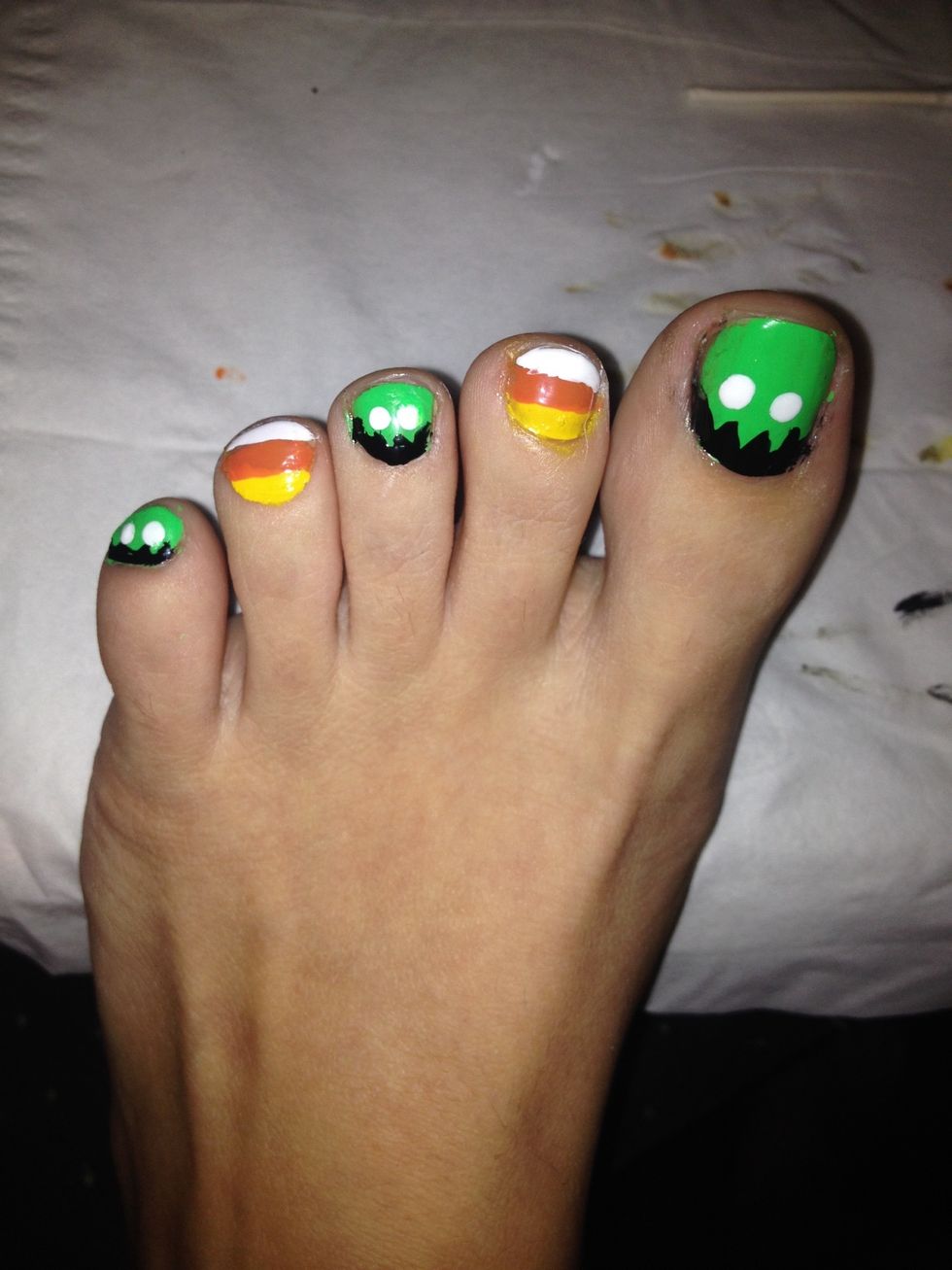 Dip the circle shaped tip into the white paint and use it to make eyes on your green nails for eyes. Use your white polish(with a brush) and swipe the white line at the tip of your candy corn nails.