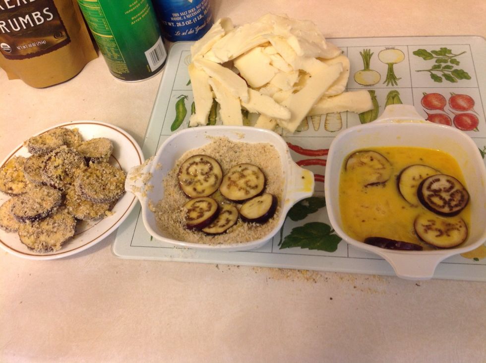 Dip the eggplant slices in the eggs, then dip and coat in the breadcrumb mixture (I mix plain breadcrumbs with Parmesan cheese and a mix of dried Italian herbs, the ratio is at your discretion).