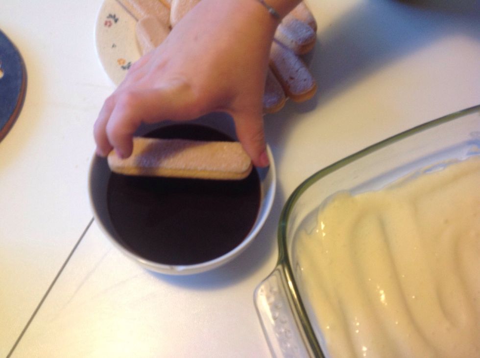 Dip the ladyfingers in the coffee slightly and place them on the cream