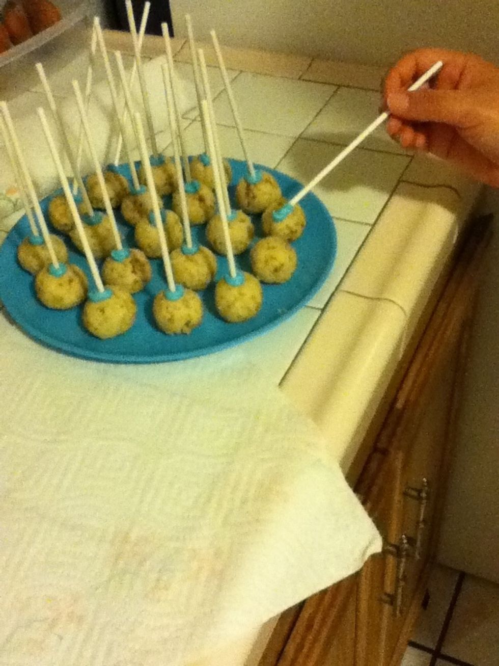 Dip the lollipop stick into the melted chocolate and insert into the cake ball