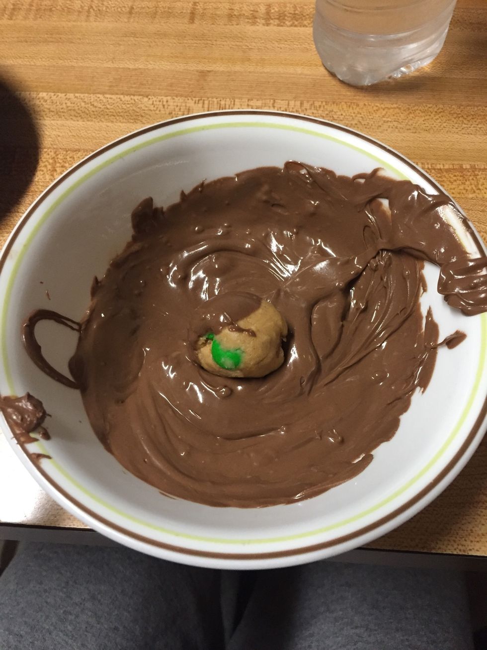 Dip the peanut butter balls into the chocolate and place them on the cooking sheet.