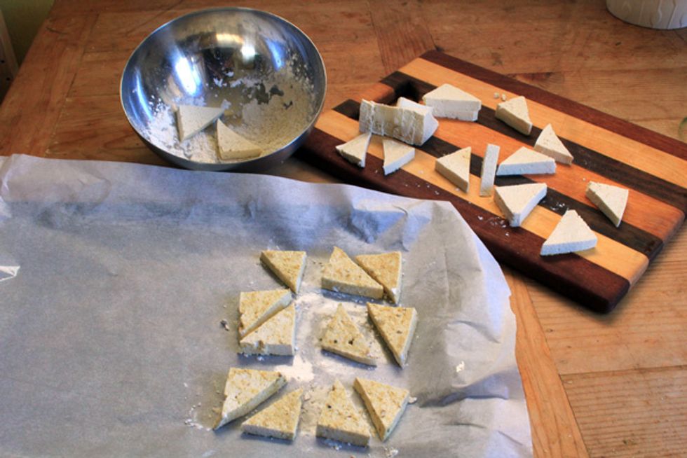 Dip the tofu triangles into the dry mixture and coat them evenly. Gently shake off any excess coating, and place the coated tofu triangles on the prepped baking sheet.