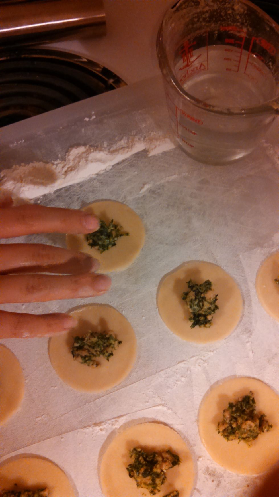 dip your finger in water and run it halfway around the filling then fold in half and press firmly to seal it up once sealed take your two corners and wrap them around to meet and press them together