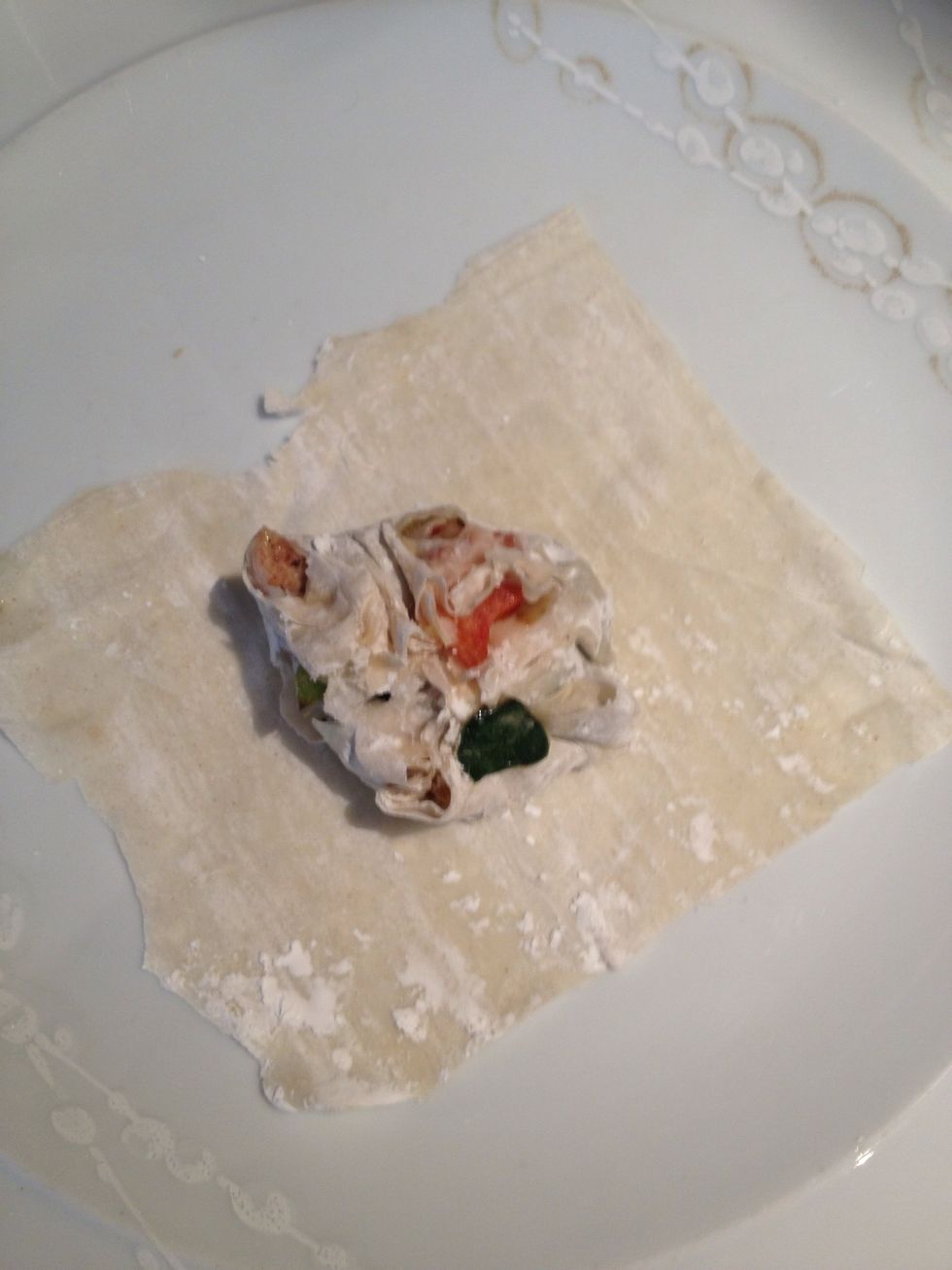 Dip your finger tips in the egg and squish your chicken, veg and filo into a rough ball. Create more squares from the filo pastry and then place your squishy ball into the middle of the filo squares.