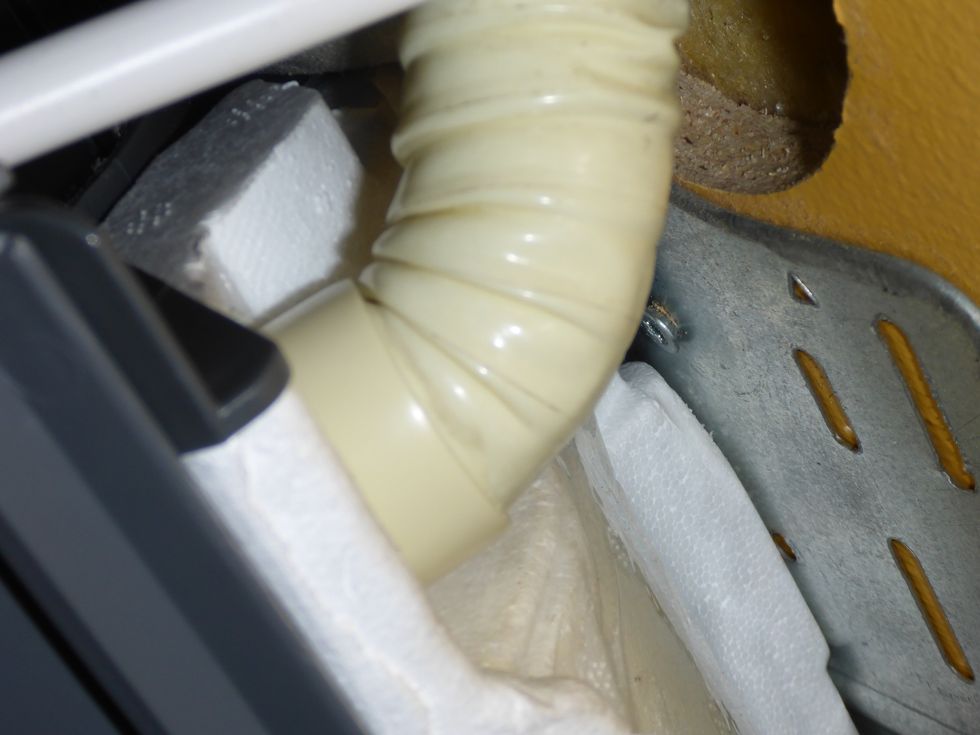 Disconnect the drain hose from the crossfan assembly by wiggeling and pulling towards the wall. Notice that some units have a locking screw on the drain hose connector. Use a mirror/camera to peek.