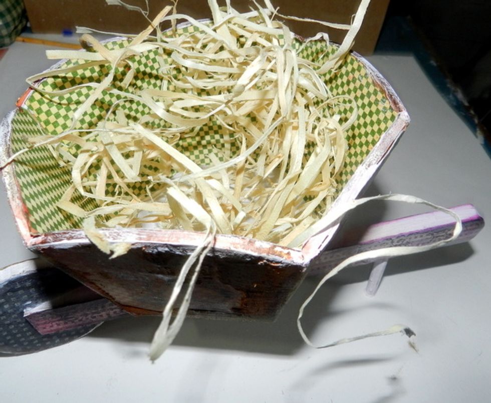Distribute a little straw into the wheelbarrow.