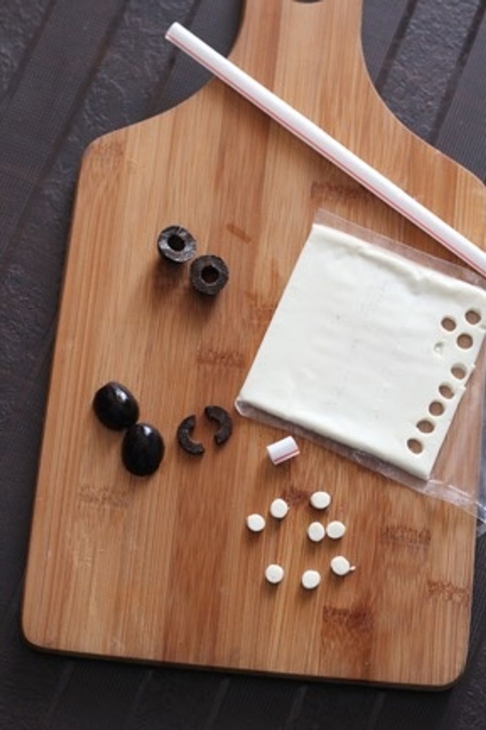 Divide 1olive into vertical half for making eyes and nose .Slice and divide the second horizontally for making moustache. Cut a few tiny circles from cheese slice using a piece of drinking straw.