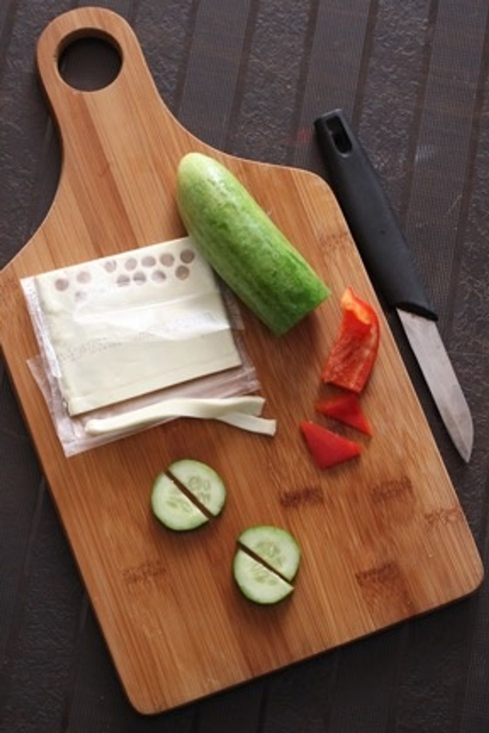 Divide 2 cucumber slices in half for the cloud and boat. Cut a thin cheese strip for making the waves and a small red pepper triangle for mast.