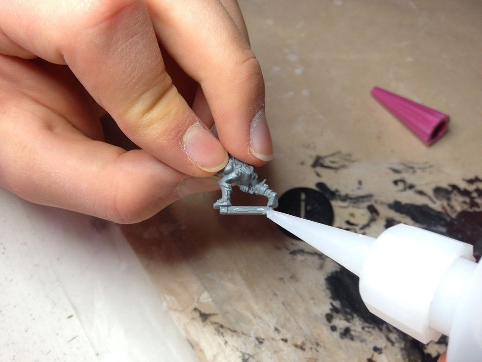 Don't get any on the model itself and be quick. If the glue bonds before you've glued it to its base, it'll be a lot more difficult to do so.