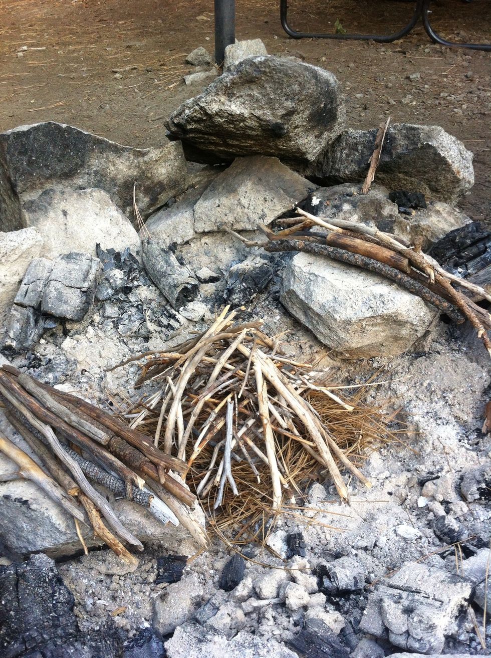 don't overdo this, it must stay erect! you don't need to use all that you have gathered. now, you want the rocks on the side to be higher than the pile, so add sticks for height if you need to.