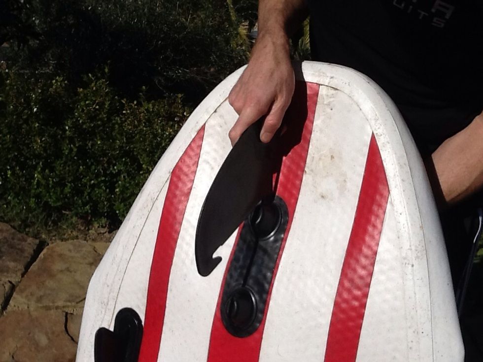 Double Fang - Step 1 - insert the back of the fin into the back slotted knob. Remember that the board must be deflated as much as possible.