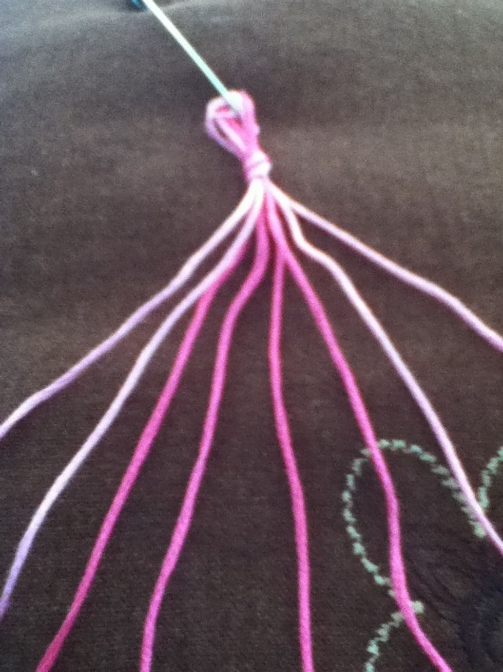 Double your strands, tie a knot leaving a loop,   and safety pin it to your work surface.