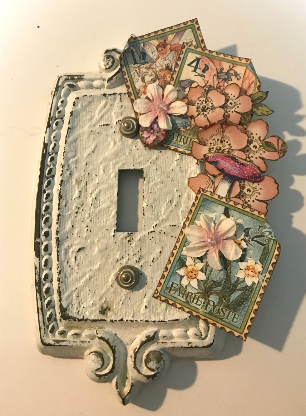 Down the right hand side, adhere 2 more flowers, a toadstool and a stamp. Roll one of the corners down  on the stamp.