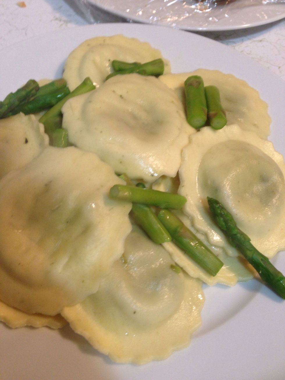 Drain ravioli, place it in a plate and tuck the asparagus between the ravioli.