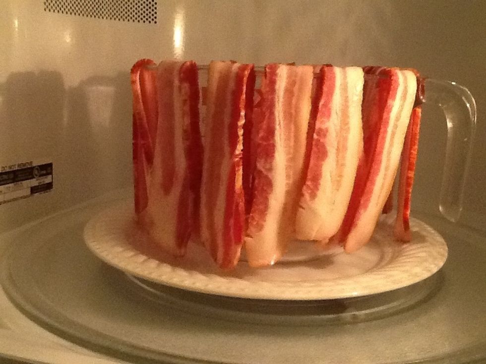 Drape bacon on microwave safe bowl over larger microwave safe plate. Place in microwave. Cook until crisp. You can cover with an optional paper towel.