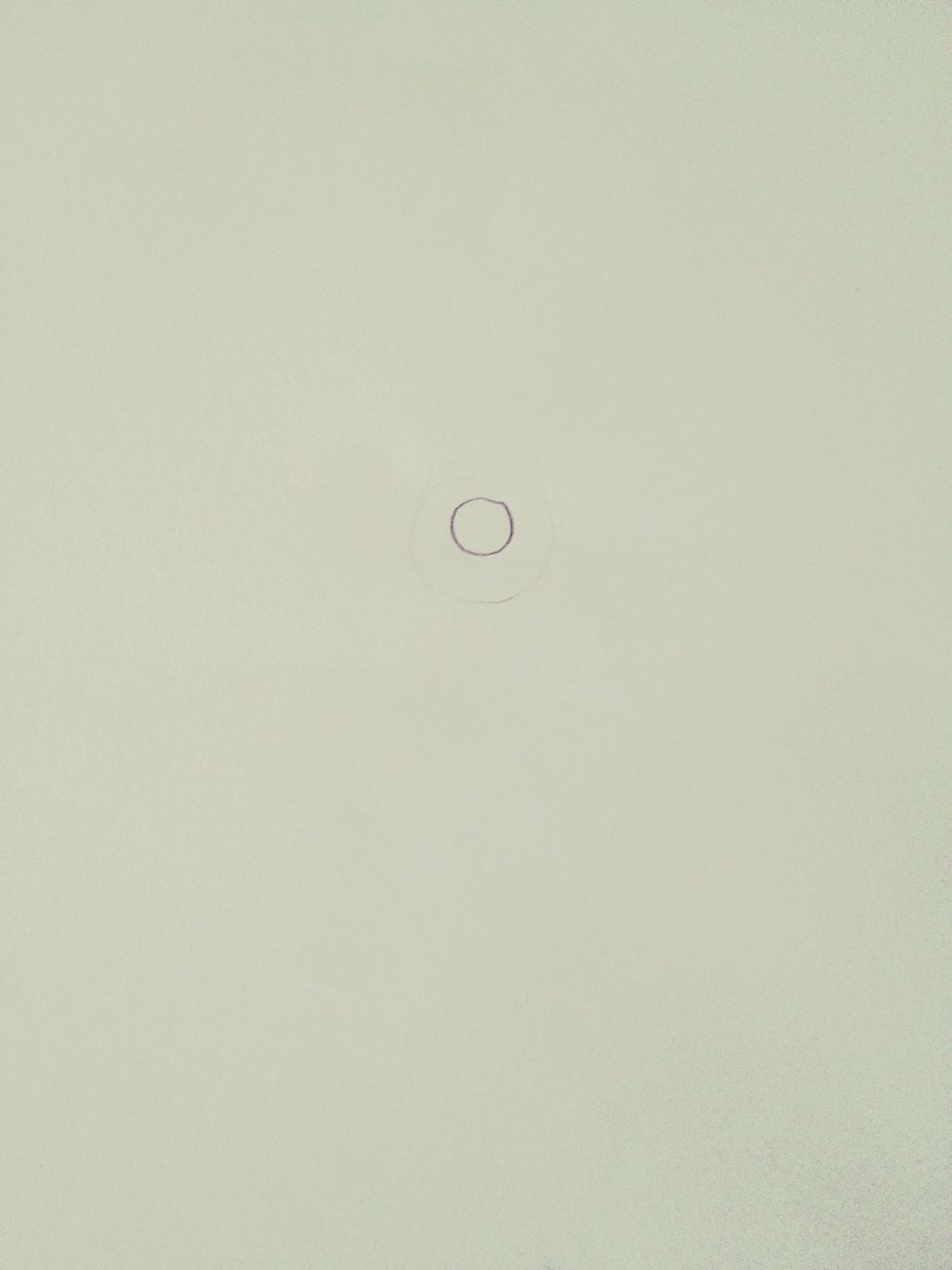 Draw a small circle in the middle of your page with pencil.