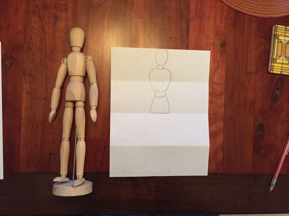 Draw Bob's hips. Bob's hips are a little wider than his waist. Bob's hips should come to the middle fold in your paper.