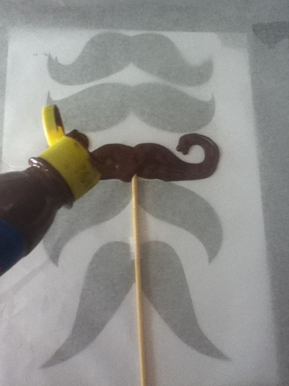 Draw with the chocolate in the mold and put more chocolate where is the stick to hold the mustache on it.