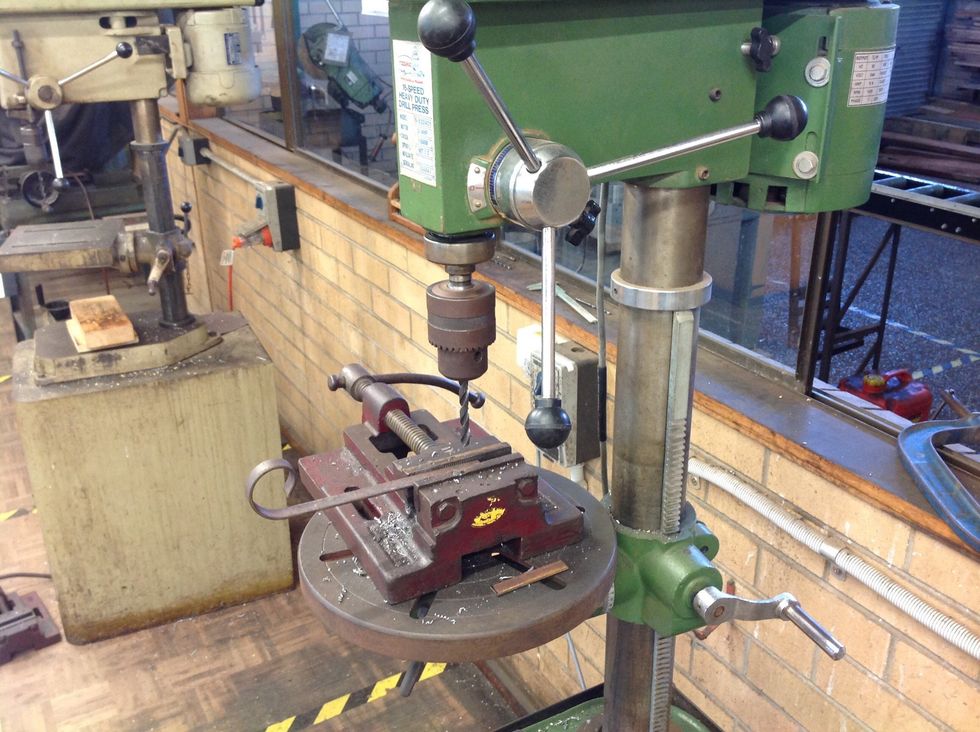 Drill one hole in the centre of the 8cm piece of the flat bar and another hole about 1cm from the edge of the scrolled of flat bar....