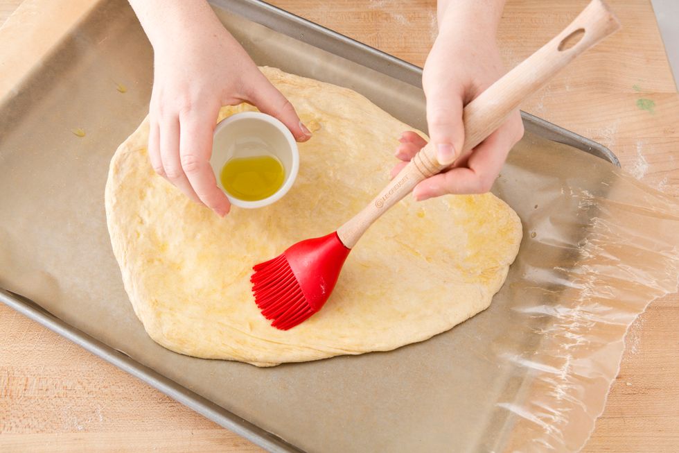 Drizzle olive oil on the dough. Pro Tip: use your fingers or a pastry brush to get it fully covered - especially the edges.