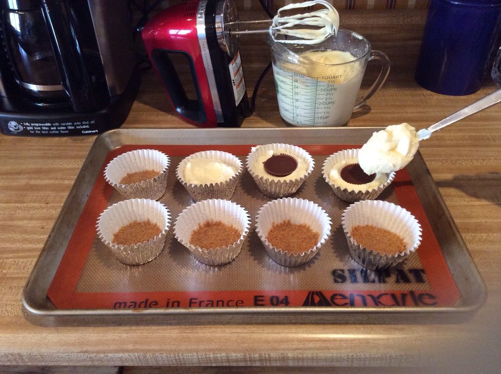 Drop 1 heaping Tablespoon of cream-cheese filing over crumb crust. Then place one Reese cup to each cupcake. Press Reese firmly down, then add another teaspoon of filing, enough to cover reese cup.