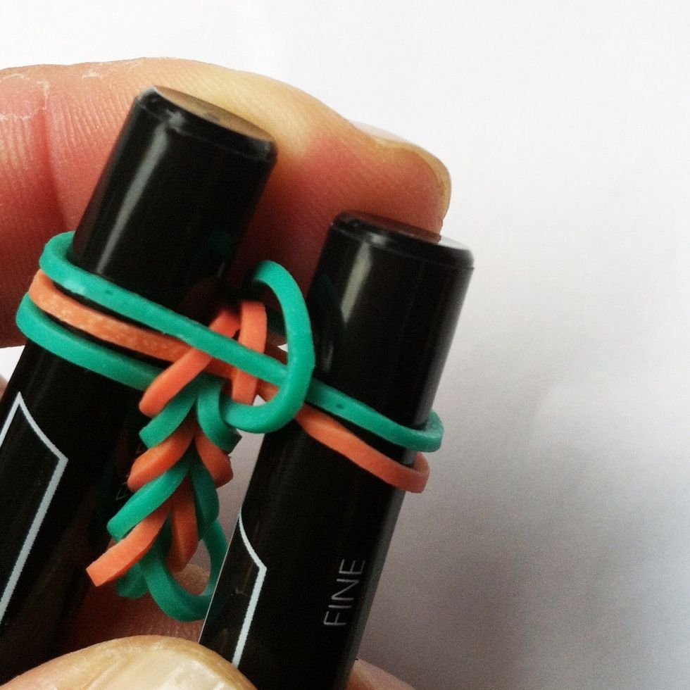 Drop the elastic in the center. Pull the bracelet in the center between the pens to stretch out and settle the placement of the elastics.