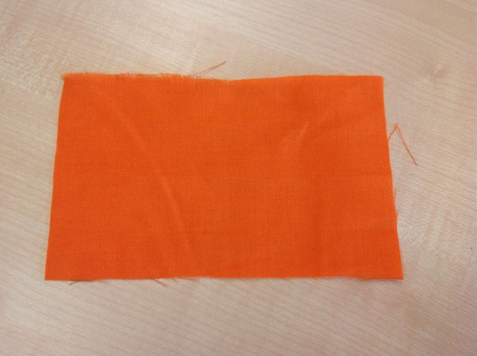 Du beh\u00f6ver en \u00f6gla f\u00f6r att f\u00e4sta snodden i l\u00e4ngst ner. Klipp till en rektangel i tyg som \u00e4r 10 cm p\u00e5 ena h\u00e5llet och 12 cm p\u00e5 andra.