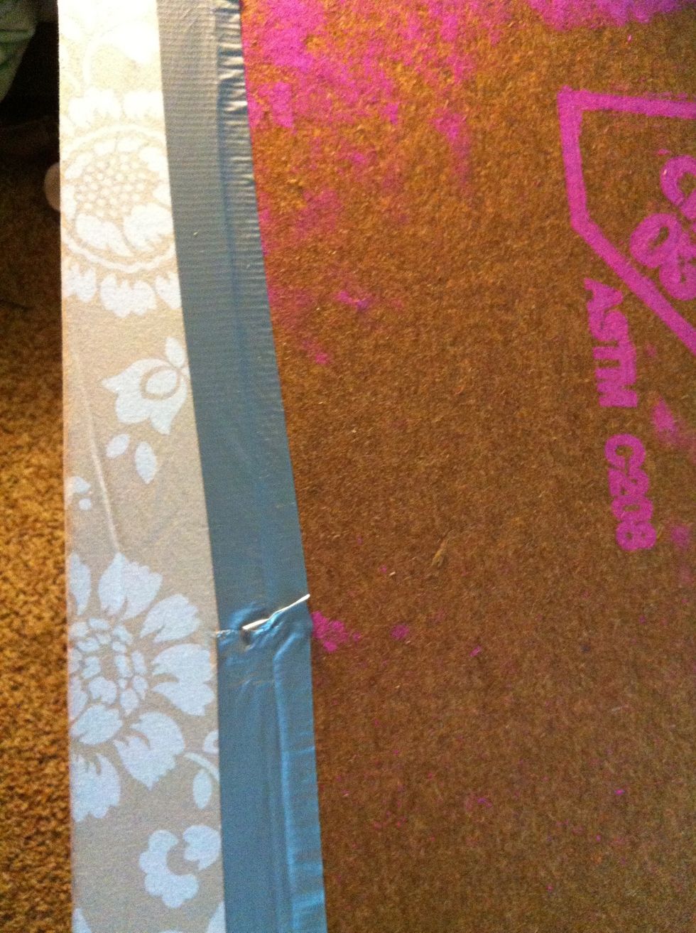 Duct tape the excess fabric to the back, pulling tight as you go. Do one side, fold a corner, another side, etc all around. I'll explain how to do neat corners.