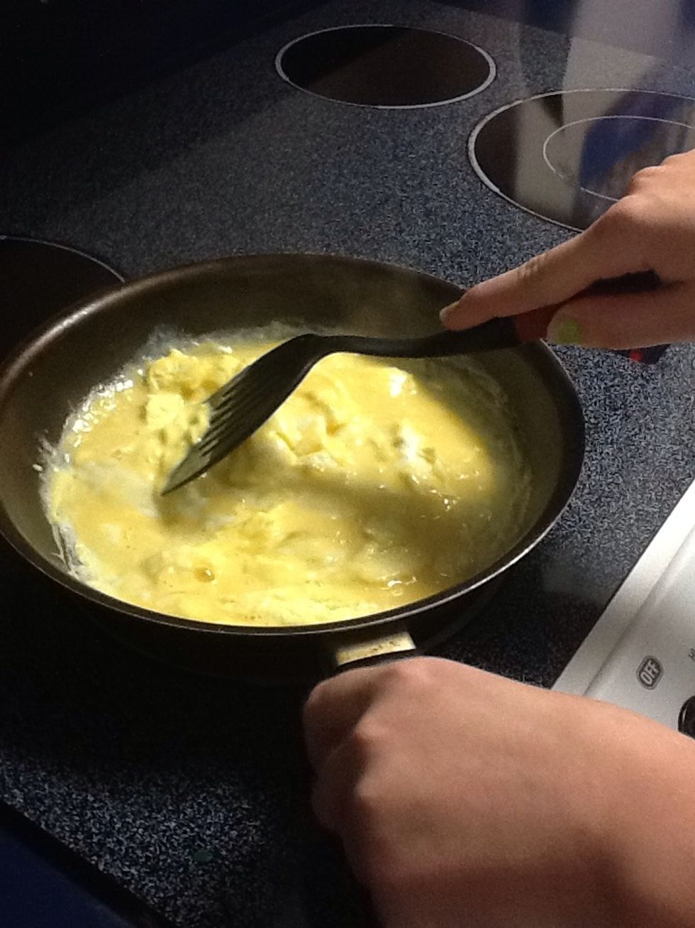 Eggs will start to cook. Use the rubber spatula to pull the eggs toward the center of the skillet.