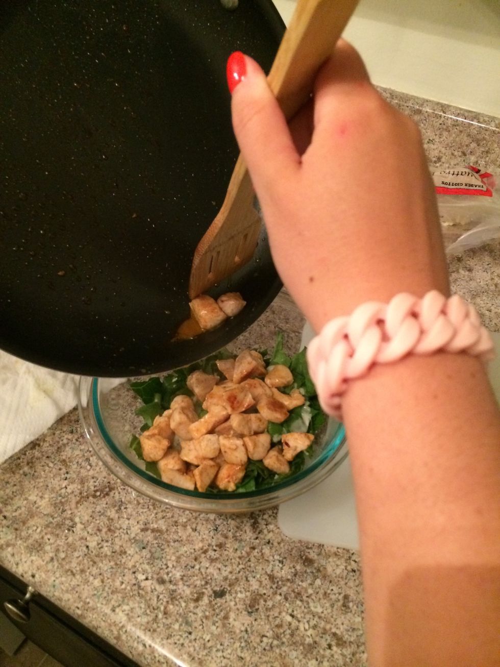 Empty the saut\u00e9ed chicken into the caesar salad bowl.