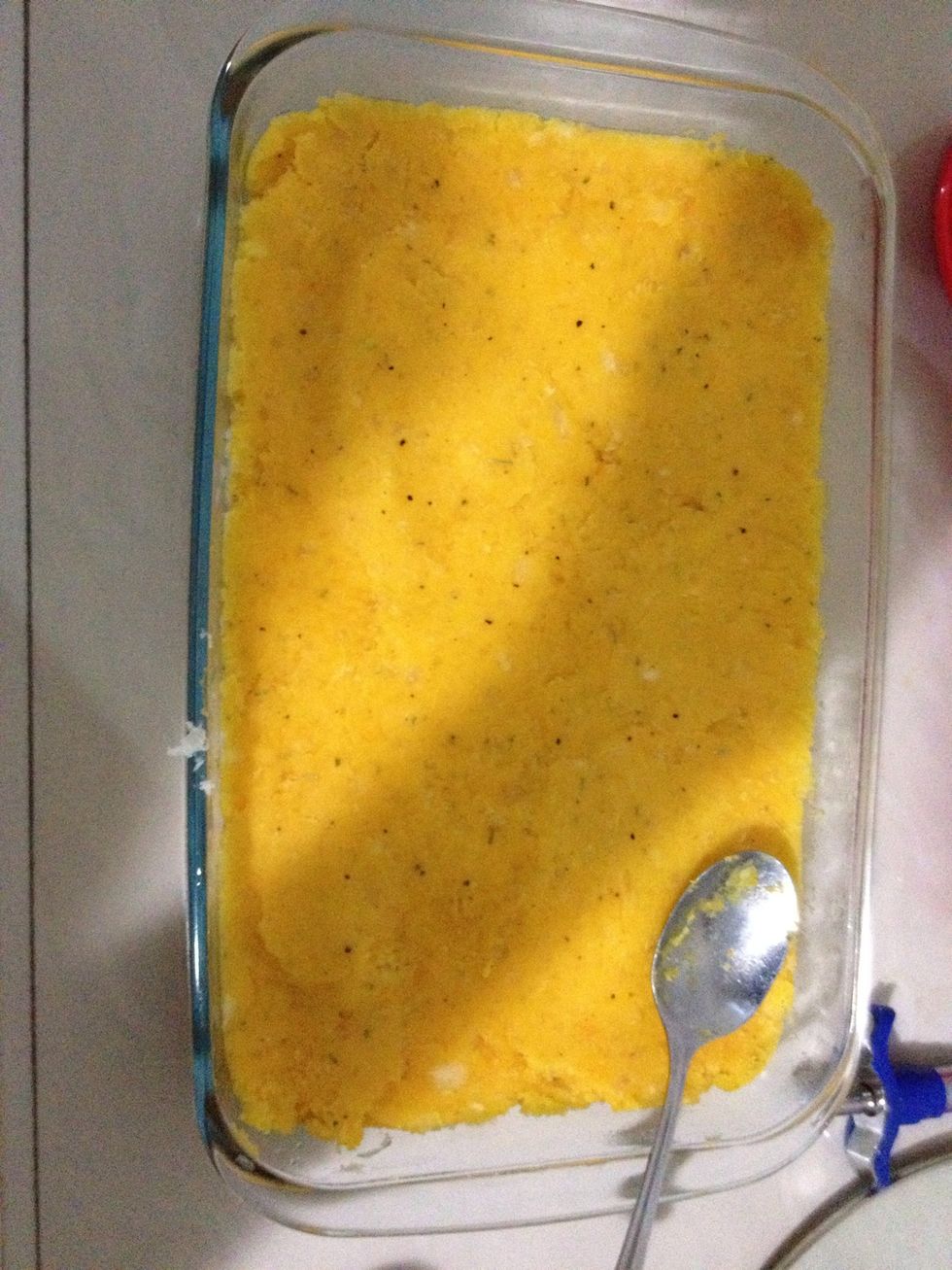 En un Pyrex hacer una capa del pur\u00e9 de yuca preparado previamente.
