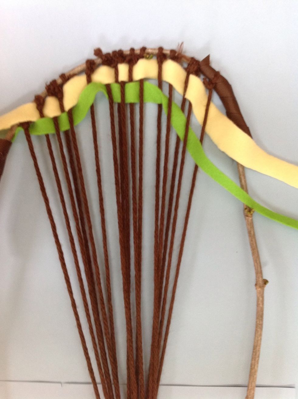 Enter your second row of "weft" through your warp. You will weave opposite of the first row. If your first begins with an over, then your second begins with under. Leave 3 inch tails on both sides.