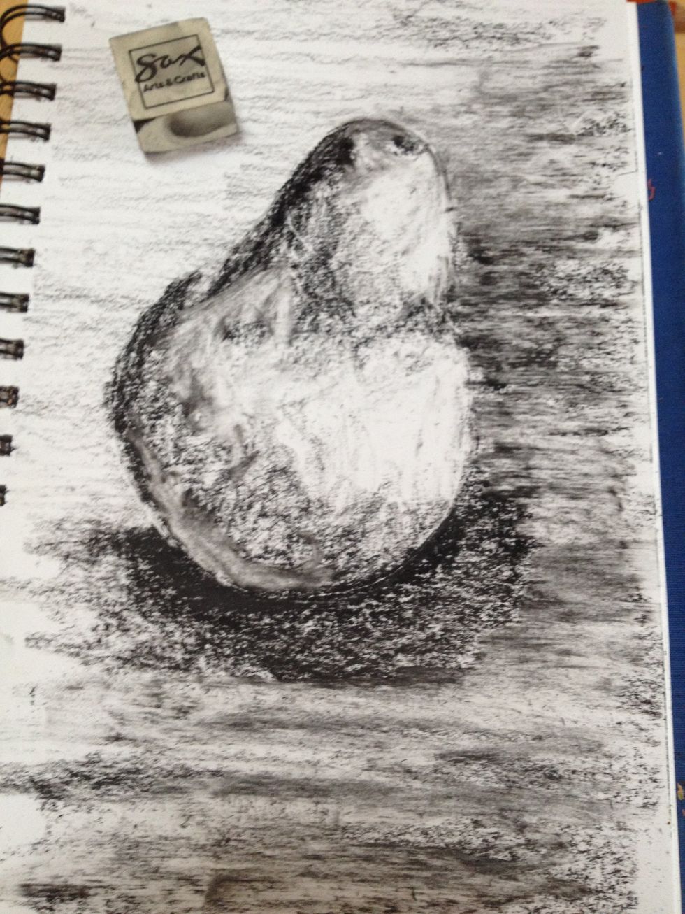 Erasers make great mark making tools in addition to allowing you to pull out highlights and giving a texture contrast between objects. I am working the highlights, orange area of the pear and table.