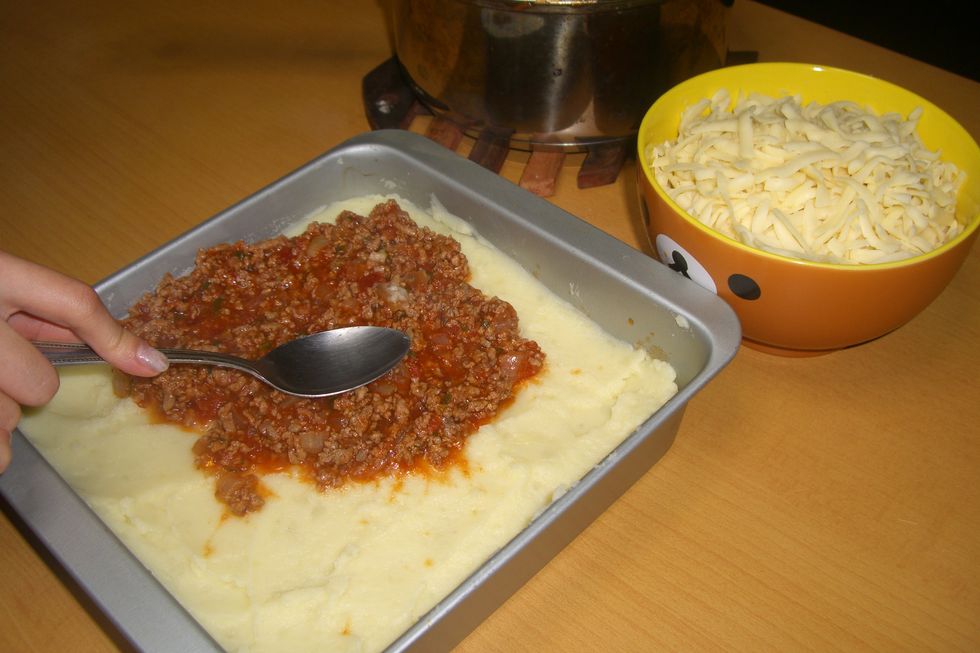 Espalhe o molho de tomate por cima do pure de batatas.