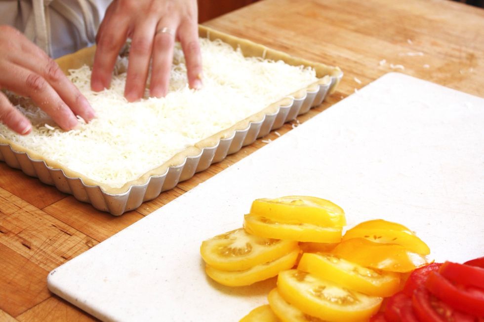 Evenly distribute the shredded cheese over the bottom of the tart mold.