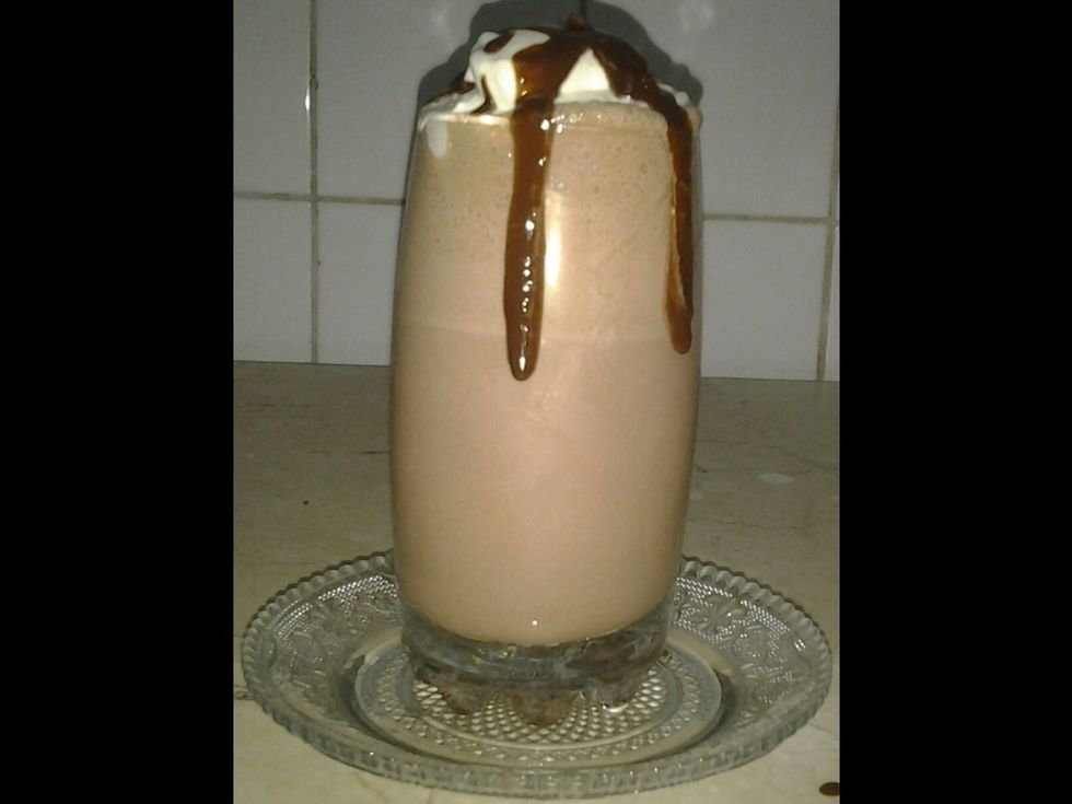 Evenly, spread out two tablespoons of runny chocolate syrup on top of the rich whipped cream to decorate the wonderful iced chocolate.