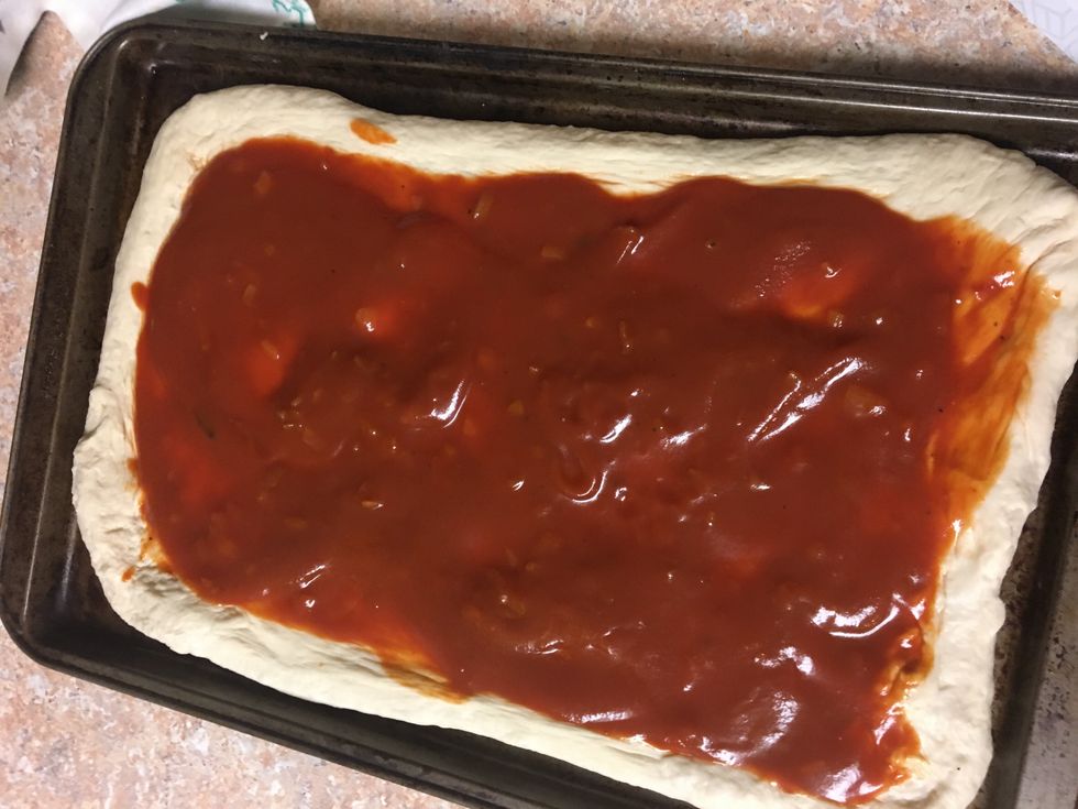 Evenly spread the sauce onto the dough, leaving a one inch border around the edges.