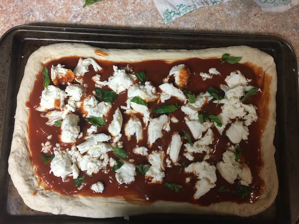 Evenly top the sauce with the prepared garlic oil, mozzarella cheese, and 1/4 of basil.