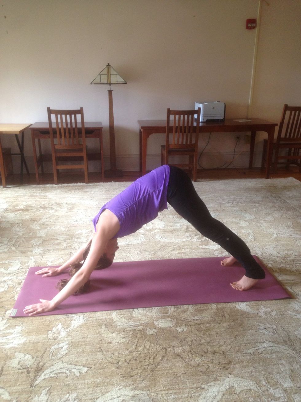 Exhale into Down Dog. Feet hip-distance, heels sink down, and hips lift up. Hands press into floor and arms extend to create a straight line through the arms and lengthened back.