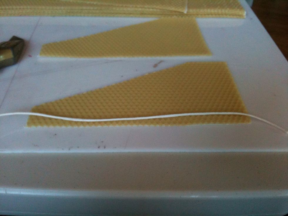 Extend one piece of wick evenly across the bottom of the sheet of wax, about 1/8 inch above the bottom edge.